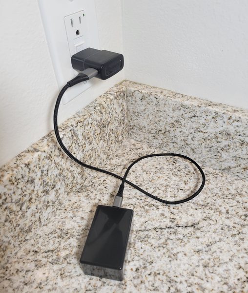 The Activity Sensor on a kitchen counter, plugged into a wall outlet with an ordinary USB adapter.